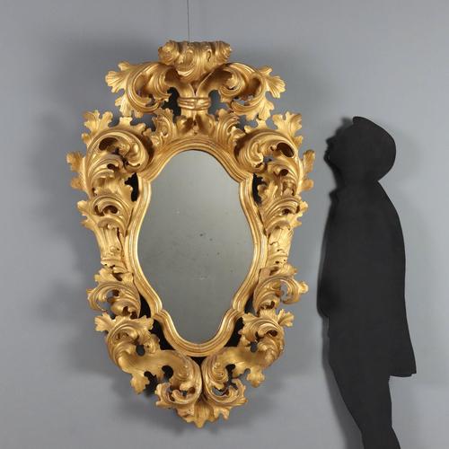 Baroque-style mirror in carved and gilded wood. The central mirror is shaped with a richly decorated molded frame...