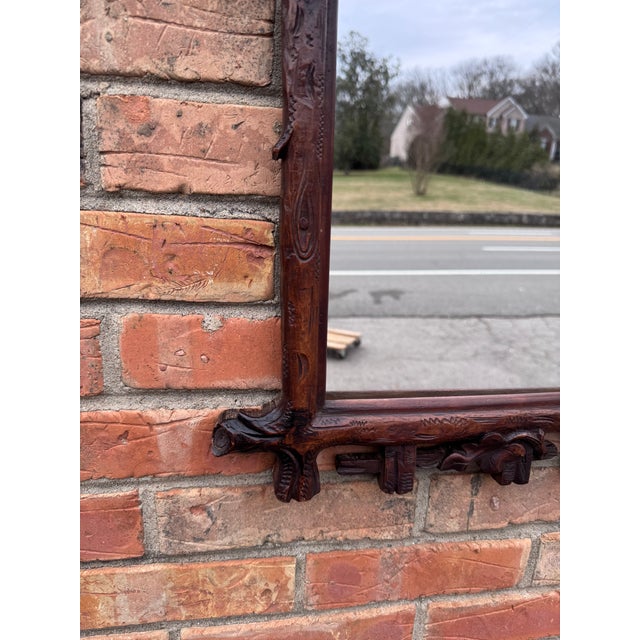 A finely carved Black Forest antique mirror featuring rich foliate details and a sculpted bird crest, hand-carved in dark-...