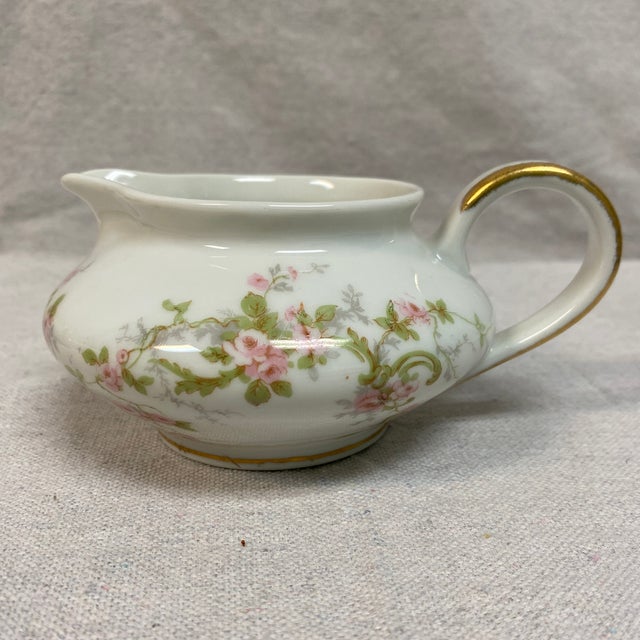 Features a delicate pink and lavender floral garland design with gold trim on the handles and rims. The creamer measures 6...