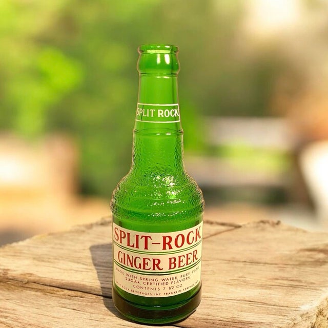 This is a circa 1960s Split Rock Beverages ginger beer bottle in textured green glass with its original applied paper...