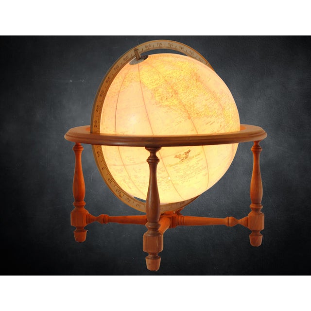 Mid 20th century lighted globe lamp featuring a traditional world globe mounted within a turned wood stand. The classic...