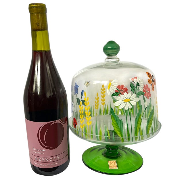 A charming and whimsical hand-painted crystal cloche by Royal Danube, Romania, featuring a vibrant meadow scene with...