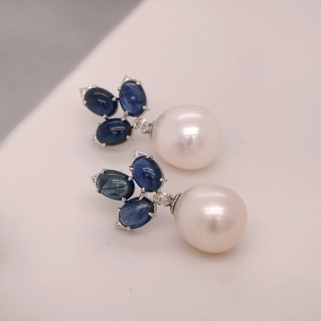 Set in platinum, these earrings feature clusters of cabochon sapphires accented with diamonds, leading to large white...