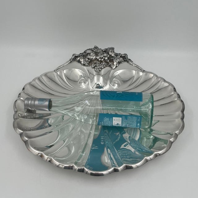 This vintage silverplate scallop shell serving dish was made by Reed & Barton, in the USA, circa the mid-20th century. It...