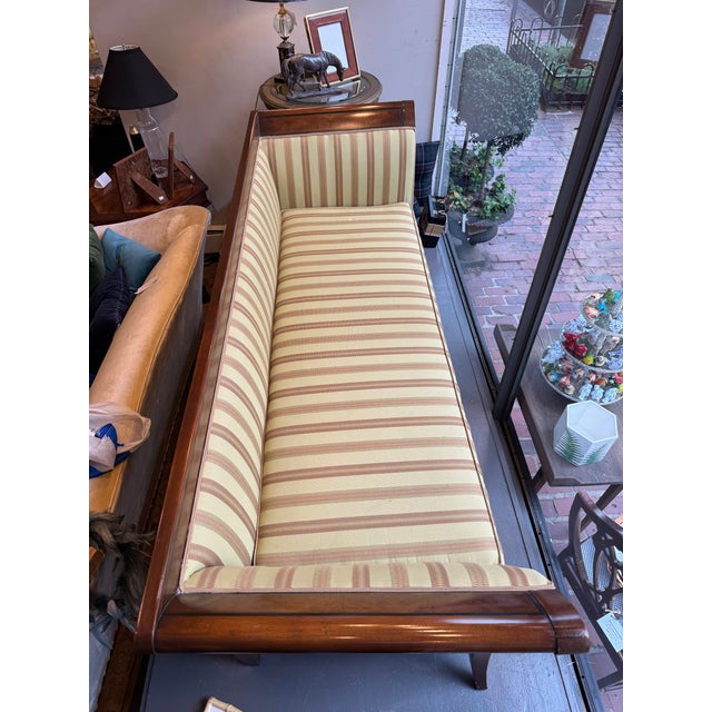 This is a late 19th century antique sofa. It has a mahogany wood frame. It has distinct flared arms. It has hand painted...