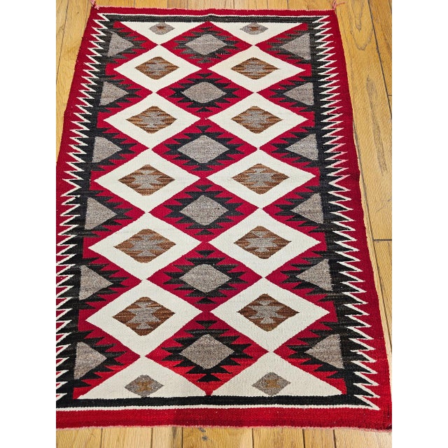 A captivating example of early 20th-century Navajo textile artistry, this vintage rug from the American Southwest...