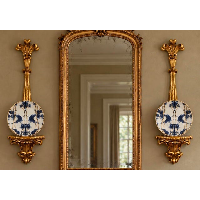 A striking pair of carved giltwood wall brackets with small projecting shelves. The elongated design features scrolling...