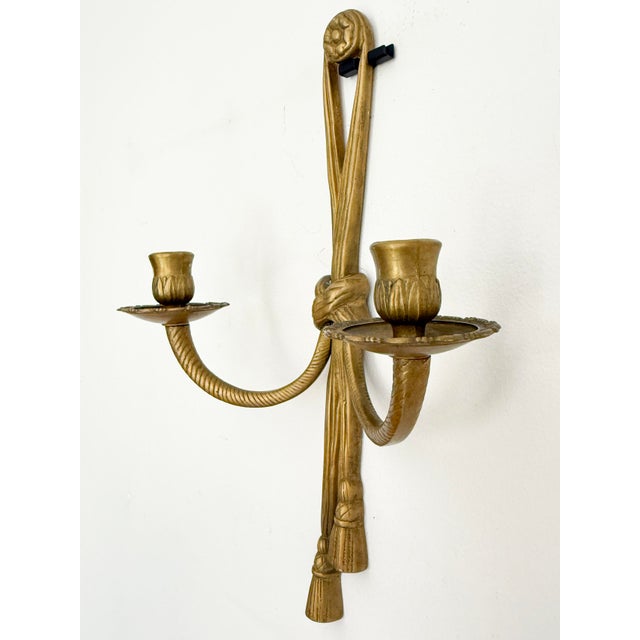 A vintage brass double wall candle sconce in neoclassical style, likely mid-20th century. the piece presents a balanced...