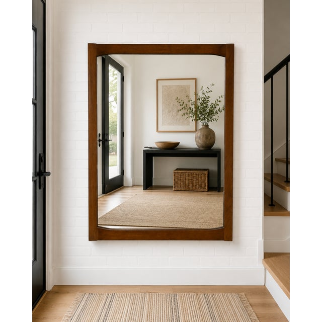 A beautifully crafted Mid Century Modern Walnut mirror, c. 1960s. This elegant wall mirror features a solid walnut frame...