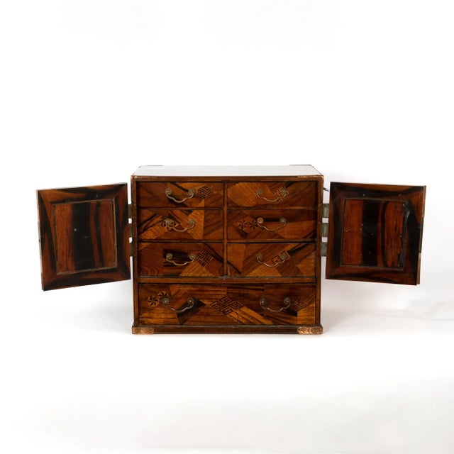 Small Japanese tansu table cabinet, circa 1900. With outstanding hardwood exterior; each door inlaid with various woods of...