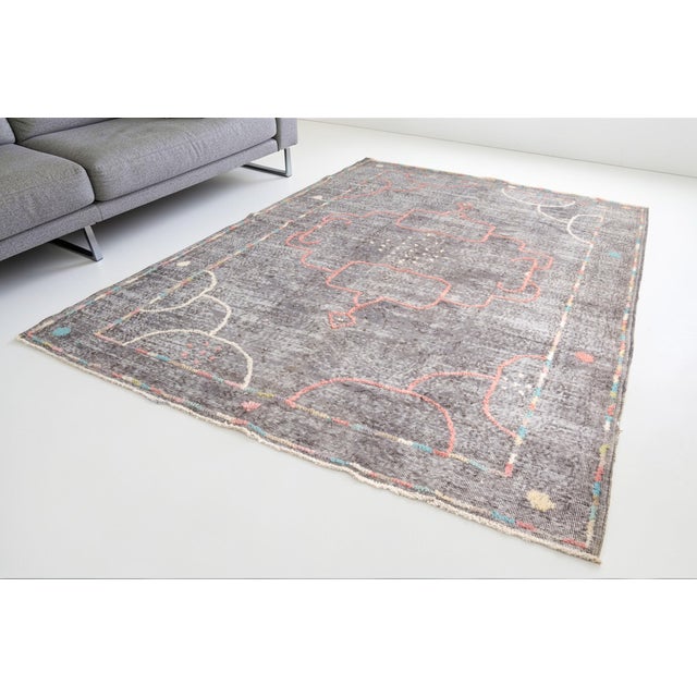This is a vintage Turkish Oushak rug from the Mid 20th Century. The piece was hand-knotted.