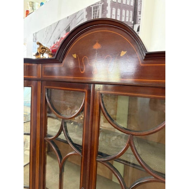 This Antique English Mahogany Display Cabinet features a satinwood inlay, making it a unique and elegant addition to any...
