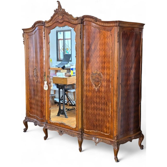 Massive ornately carved walnut Louis XV French style Armoire. Carved crest and a central mirrored door flanked by two side...
