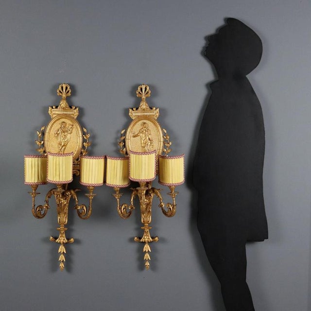 Pair of Neoclassical-style wall lamps in carved and gilded wood, iron, and pastiglia. Central medallion depicting Vestal...