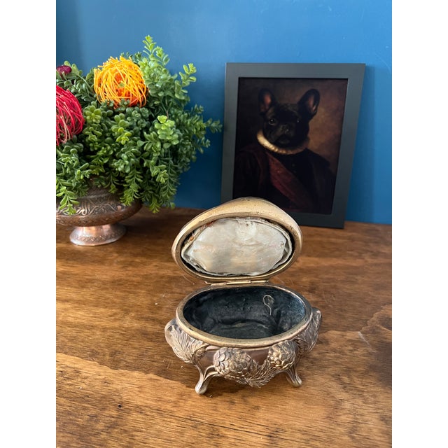 Elegant vintage Art Nouveau style jewelry casket featuring ornate raised detailing and a sculptural footed form. The...