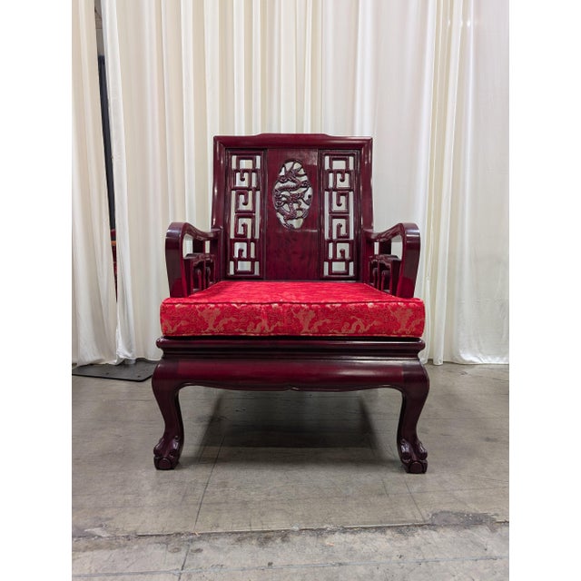Vintage Chinese solid rosewood armchair with a hand-carved, pierced dragon medallion set into a key-fret lattice back,...