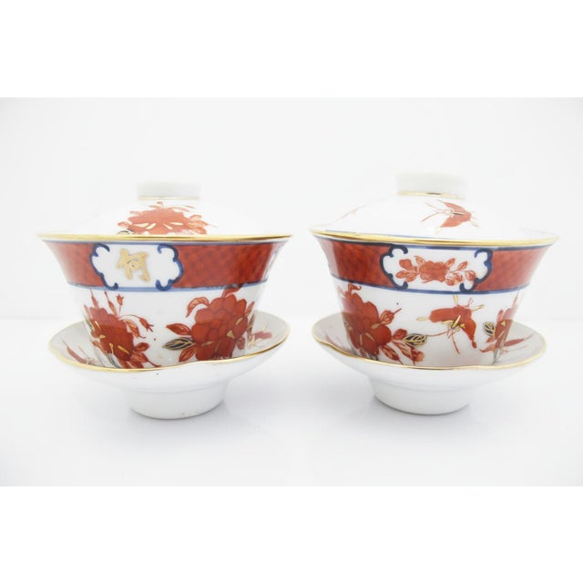 Beautiful pair of Japanese lidded tea bowls with saucers. Each in white porcelain, with hand painted floral and butterfly...