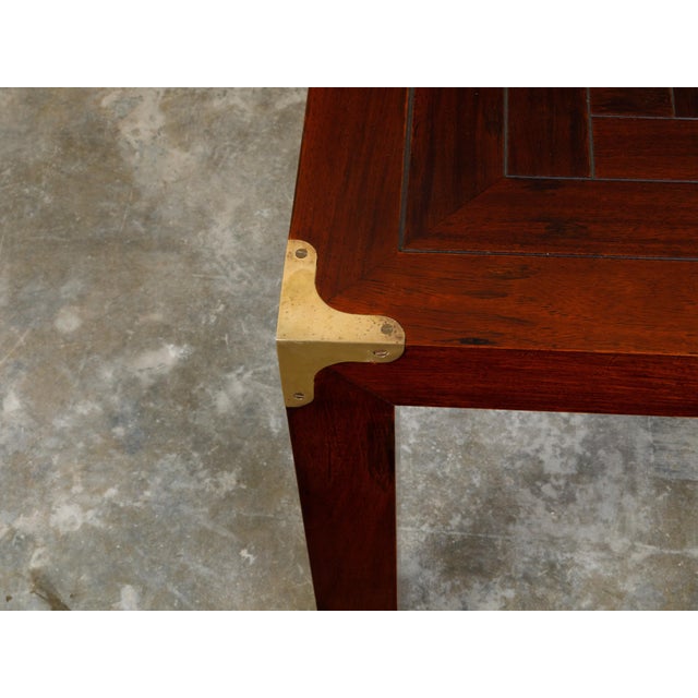 An English Campaign style walnut side table from the mid 20th century, with parquet style top, brass accents and straight...