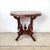 An elegant Victorian Revival center table featuring a richly veined oval marble top above an elaborate carved walnut-toned...