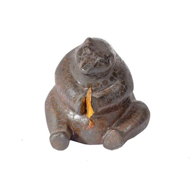 A raku pottery bear by American artist Tony Evans (1942-2009). This piece depicts a bear holding a copper fish in between...