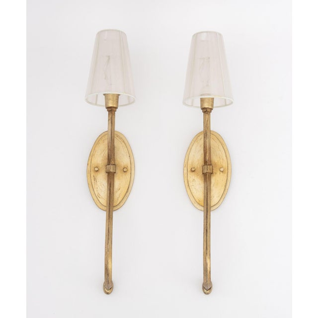 Pair of Hollywood Regency Style Gilt Metal Wall Sconces, each with white tulle shade. 23.5" H x 4.75" W x 7.25" D....