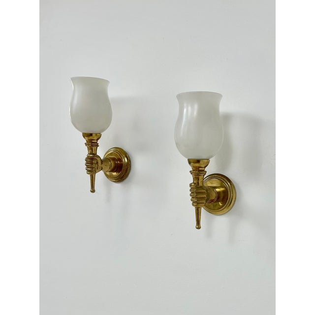 Pair of Maison Jansen wall sconces, each composed of a patinated solid brass structure in the shape of a hand holding an...
