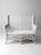 An early 20th-century wicker loveseat with a high woven back, gracefully rolled arms, and intricate open latticework. The...