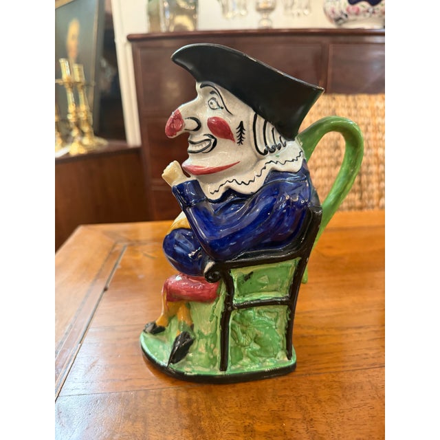 This antique 19th-century French Majolica Toby jug features the classic character of Mr. Punch, seated on a green chair....