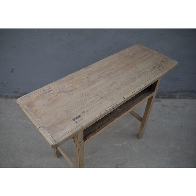 A distinctive vintage Chinese console table crafted from solid elmwood, dating to the first half of the 20th century. The...