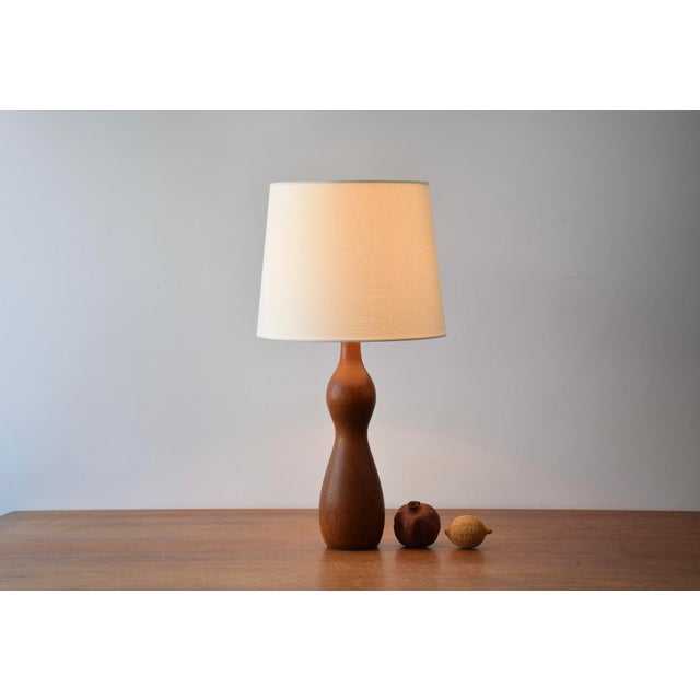 Scandinavian Mid-century table lamp made from turned teak and in the style of Finn Juhl. Made circa 1960s. The teak has a...