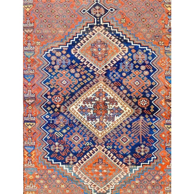 An incredible early 20th century Persian Ghashghaei rug with three large multicolored diamond medallions amidst a...