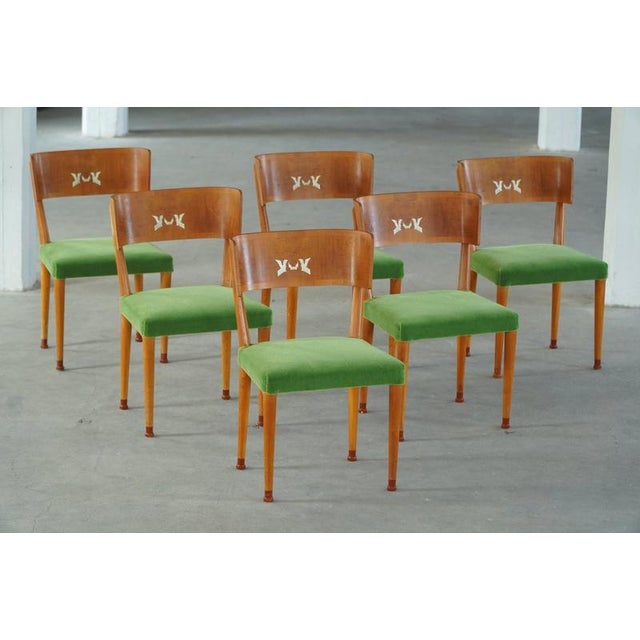 A set of six exquisite dining chairs from the 1930s, crafted in solid elm with elegantly curved backrests adorned in birch...