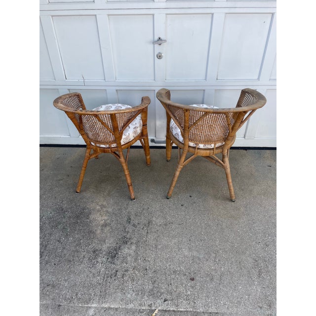 Pair of barrel back woven rattan chairs. The backs slope down into the arms creating a barrel back. The arms are woven...