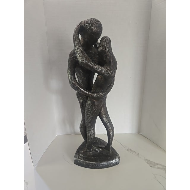 A striking modernist sculpture depicting a nude couple in an intimate, textured embrace. This piece features a brutalist-...