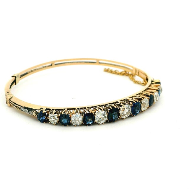 A refined mid-century bangle showcasing a beautifully balanced row of alternating sapphires and diamonds. Crafted in 14K...