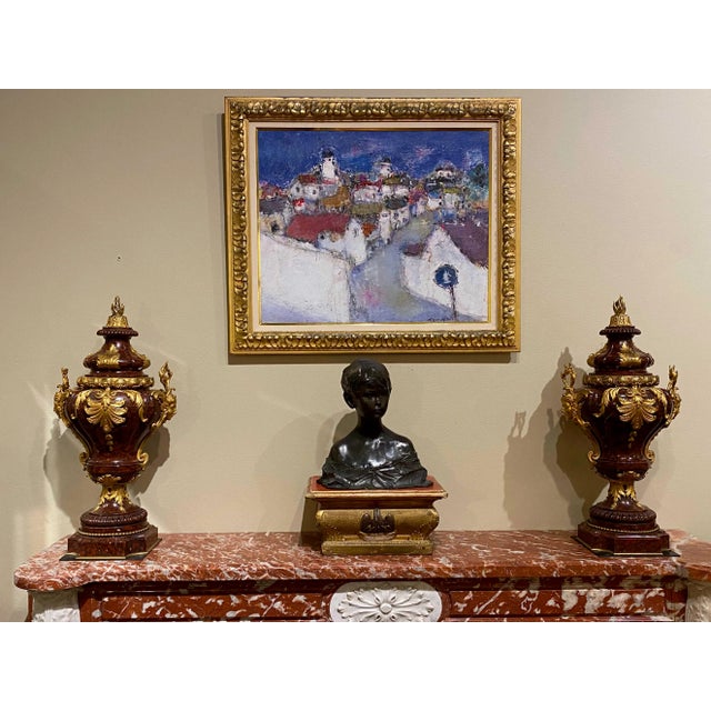 A fine pair of French ormolu bronze-mounted rouge griotte marble urns with bronze mask handles, leaves with a flame finial...