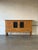 Grand architectural form features four carved doors including two leaded glass panels, four base drawers, and interior...