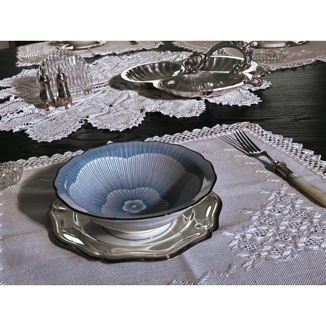 A refined set of five Japanese porcelain bowls featuring an elegant cobalt blue radiating floral motif and softly...