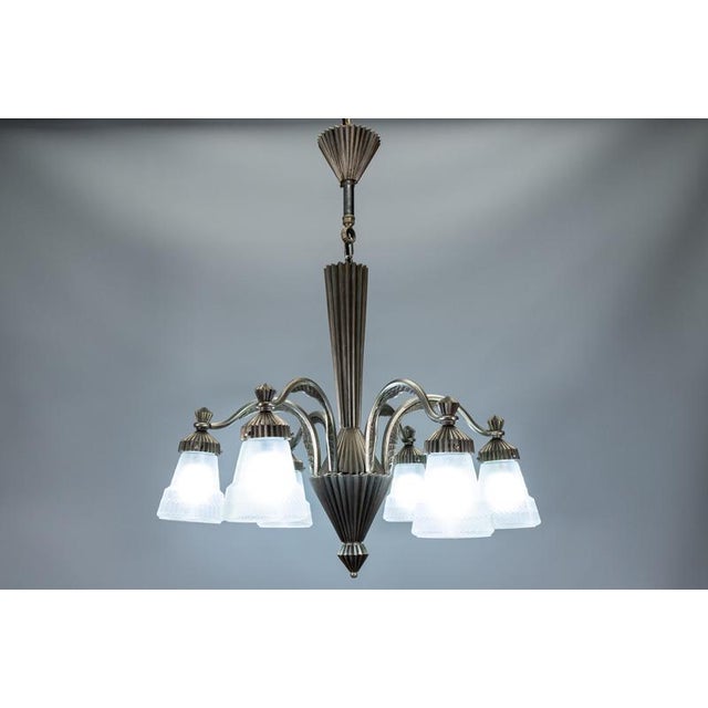 French Art Deco bronze chandelier with frosted geometric glass shades, circa 1930. Elegant six-light chandelier featuring...