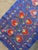 Hand-embroidered Suzani table runner from Uzbekistan — a red pomegranate vine climbing the length of a royal blue silk...