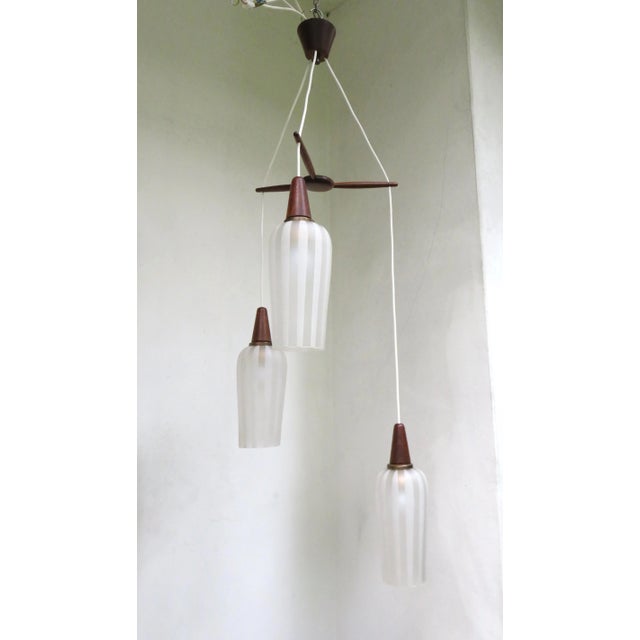 A Scandinavian cascade lamp from the 60s. Elegant combination of teak with patinated brass and glass. The glasses are...