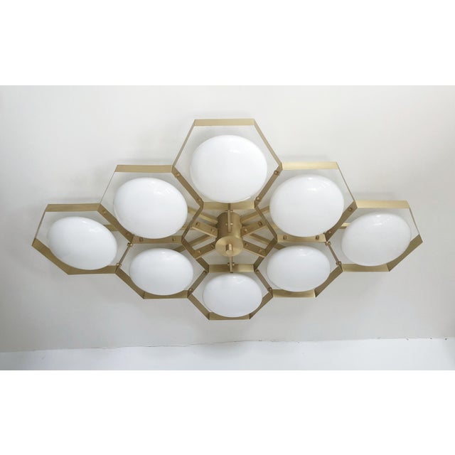 Italian midcentury flush mount with eight glossy white Murano glass shades mounted on solid brass frame in satin brass...
