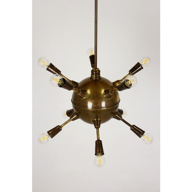 A vintage mid-century modern chandelier from the 1960s in a classic Sputnik design. It has a central brass sphere with ten...