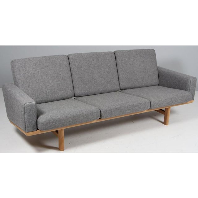 Hans J. Wegner three-seat sofa upholstered with light grey wool. Frame in solid oak. Model 236/3, produced by GETAMA. This...