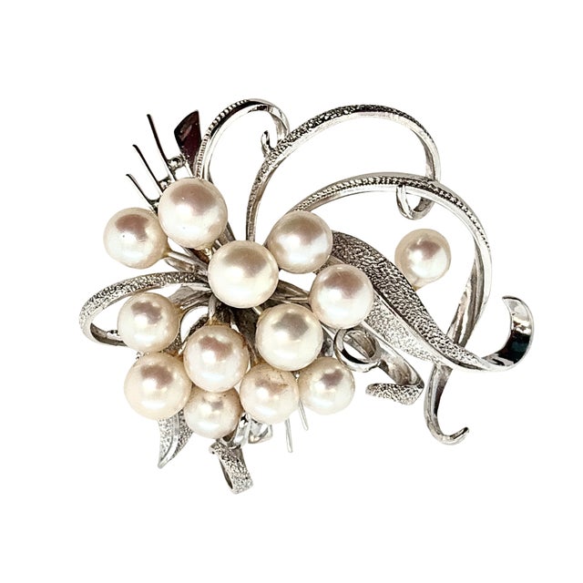 A bold vintage sterling silver brooch featuring a cluster of nine Akoya cultured pearls set within a swirling bow-like...