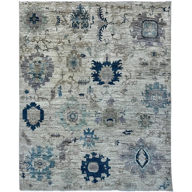 This handmade rug features an all-over floral design in navy blue, soft blue, taupe, and gray on an ivory ground. Large...