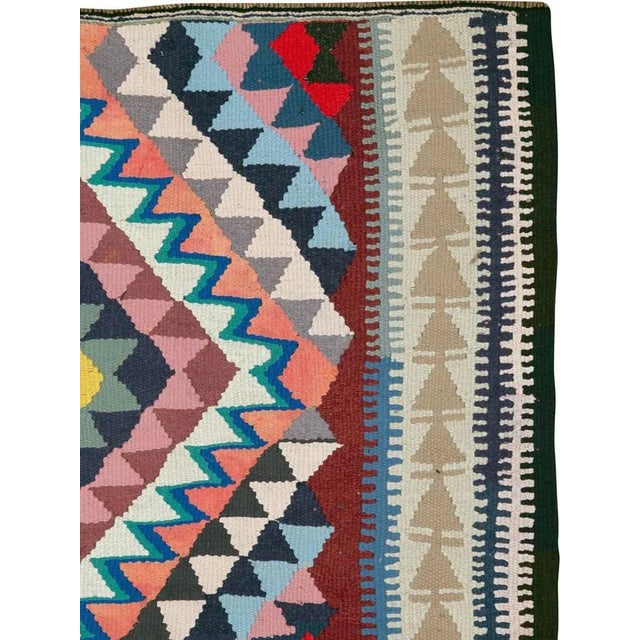 A vintage Persian flat-woven Kilim rug from the mid-20th century. A Kilim is a flat tapestry-woven carpet or rug...