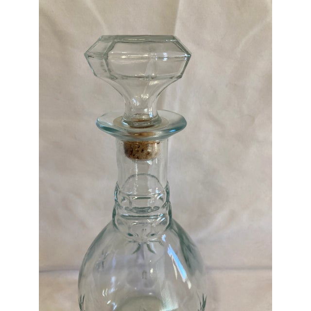 This vintage cut glass decanter showcases classic starburst detailing and a faceted stopper, offering timeless appeal and...