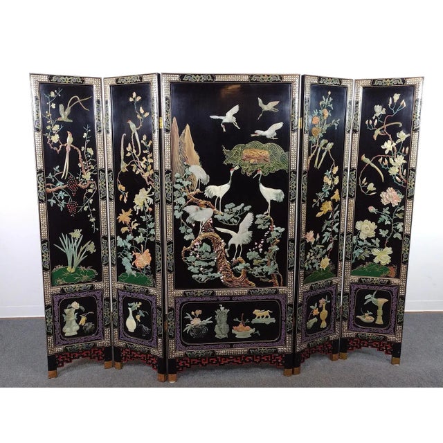 Vintage Chinese five-panel folding screen in black lacquer, richly decorated with carved hardstone relief depicting cranes...