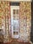 Beautiful custom floral pinch-pleat drapery panels featuring a warm beige ground with rich yellow-gold floral baskets and...